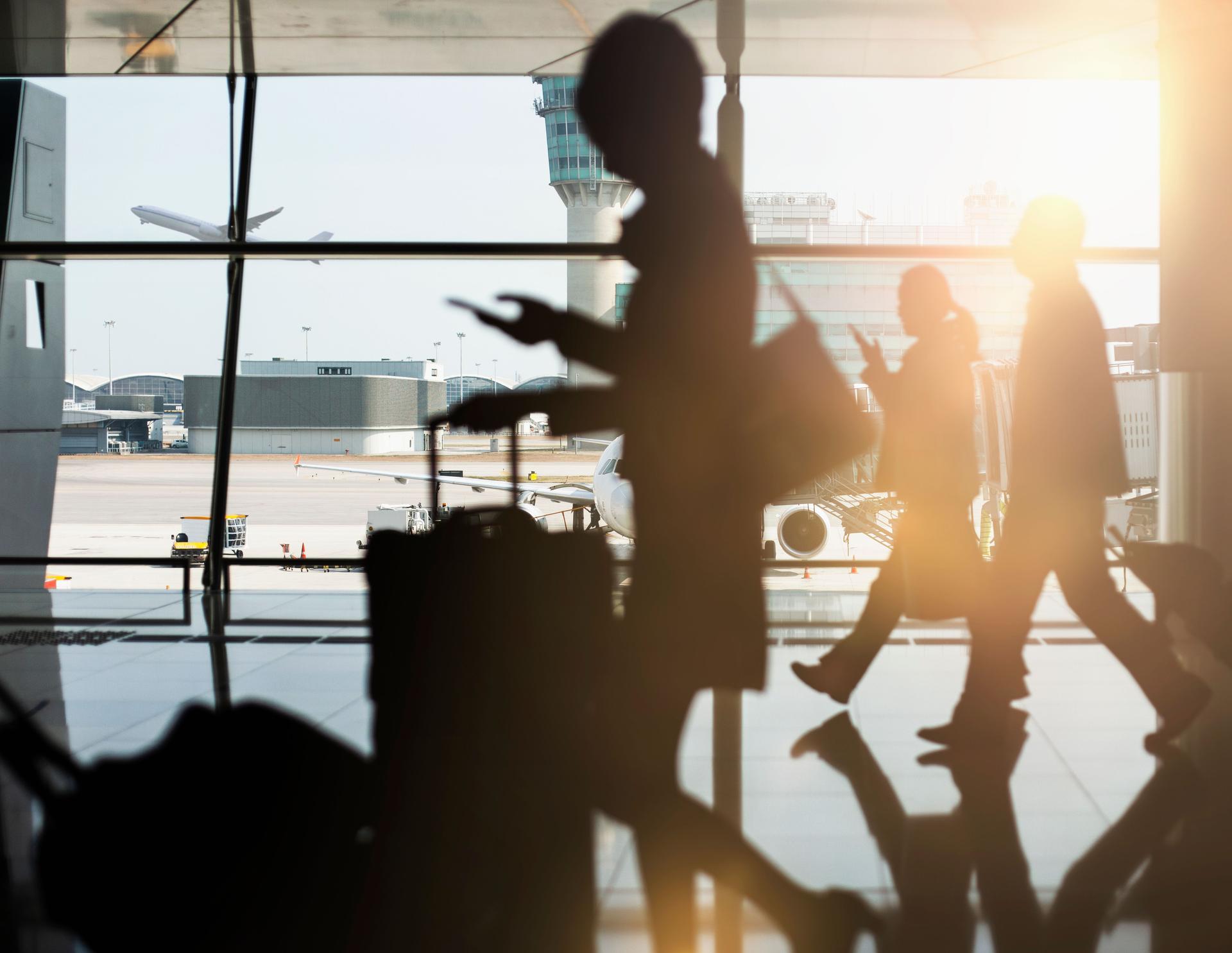 Black SUV of passengers walking and using phones in airport terminal with luggage